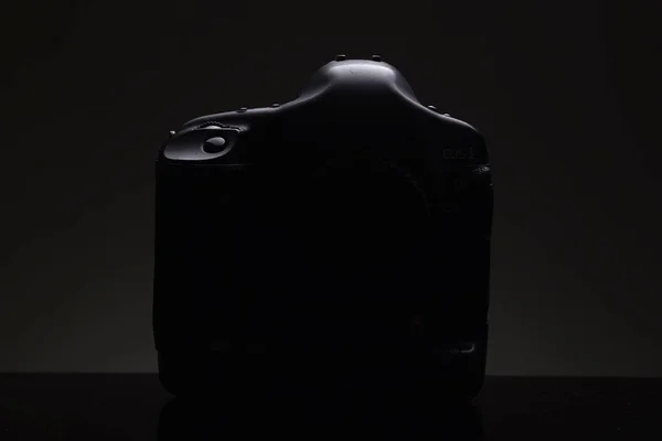 Het silhouet van een professionele SLR camera op een zwarte achtergrond. Presentatie van een nieuw product — Stockfoto