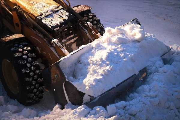 Excavadora con un cubo lleno de nieve. Eliminación de nieve de las calles de la ciudad por la noche. — Foto de Stock