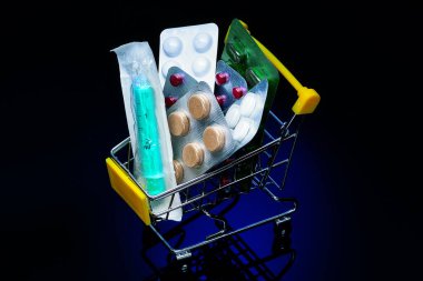 Küçük bir alışveriş arabası ilaç ve şırıngayla dolu. İlaç ve tıbbi ürünlerin satın alınması. 