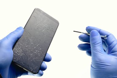 Eldivenli bir teknisyen bozuk bir telefonu tamir ediyor. Usta elinde bozuk bir ekran ve tornavidayla bir akıllı telefon tutuyor.