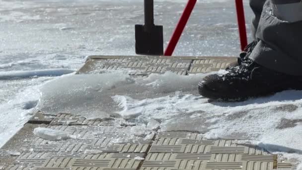 De arbeider raakt het ijs met een koevoet en spatten en sneeuwkristallen vliegen. Close-up vanaf het onderste punt van de afbeelding. — Stockvideo