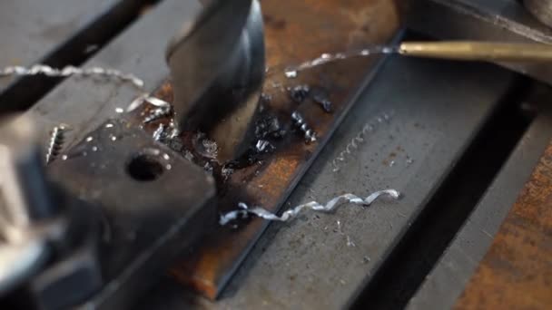 Un taladro de gran diámetro perfora una placa de metal y se forman chips de metal. Trabajando en una tienda de tornos. — Vídeo de stock