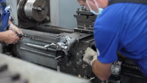 Prevención y mantenimiento de máquinas herramienta en el taller. Dos hombres caucásicos instalaron y repararon un torno. — Vídeo de stock