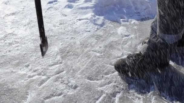 De arbeider raakt het ijs met een koevoet en spatten en sneeuwkristallen vliegen. Close-up vanaf het onderste punt van de afbeelding. — Stockvideo