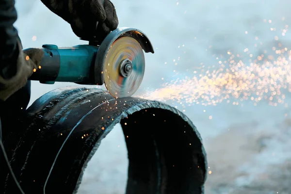 La amoladora angular corta un tubo de metal de gran diámetro y chispas vuelan. Primer plano del trabajo en la producción. — Foto de Stock