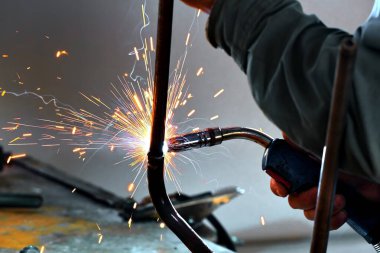 Kaynak dükkanında çalışan bir kaynakçı ve kıvılcımlar uçuşuyor. Yakın plan..