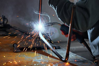 Kaynak dükkanında çalışan bir kaynakçı ve kıvılcımlar uçuşuyor.. 