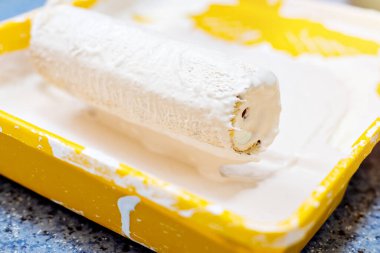 Boya silindiri bej boyalı sarı bir tepside. Tamir ve boyama konsepti. Yakın plan..