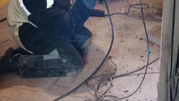 Spawacz siedzi w warsztacie na betonowej podłodze i spawa pierścienie rur żelaznych. Wysokiej rozdzielczości film wideo — Wideo stockowe