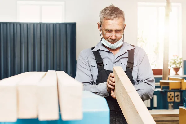 Porträtt av en äldre snickare eller snickare som arbetar med träskivor i en snickarverkstad. — Stockfoto