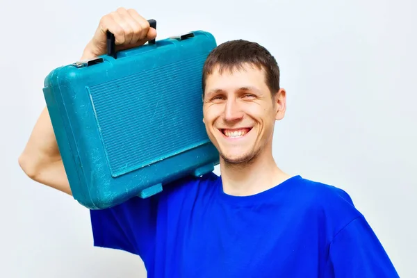 Retrato de um serralheiro positivo sorriso largo. Um trabalhador tem um estojo de ferramentas no ombro. — Fotografia de Stock
