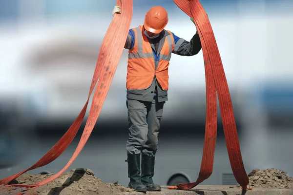 Kasklı ve tulumlu bir atıcı güneşli bir günde dışarıda çalışır. Üretimde yükleme ve boşaltma işlemleri.