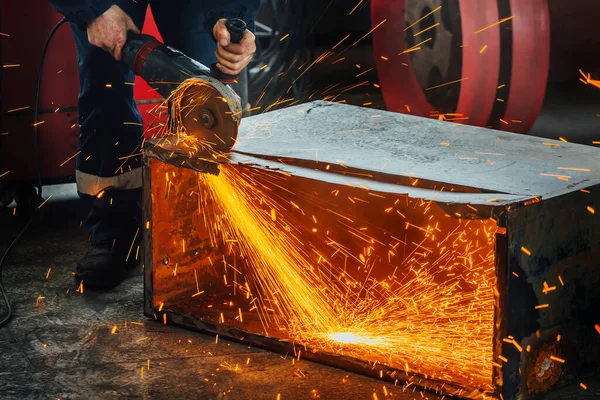 생산 공장에서 일하는 사람 이 금속을 손으로 분쇄기로 자르면 밝은 불꽃 이 튀어 오릅니다. 진정 한 작업 환경. — 스톡 사진