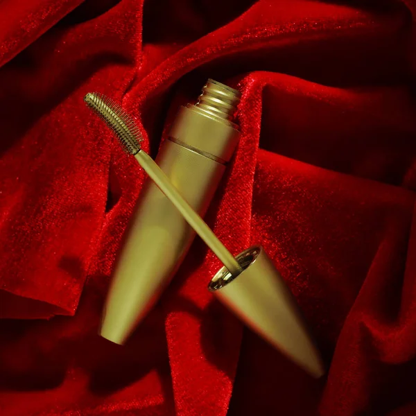 Mascara in oro su velluto rosso. Foto promozionale di cosmetici. vista dall'alto — Foto Stock