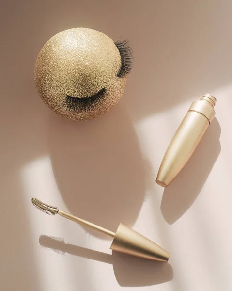 Tusz do rzęs i złoty świąteczny bal ze sztucznymi rzęsami. Koncepcja uroczystego makijażu dla kobiet. — Zdjęcie stockowe