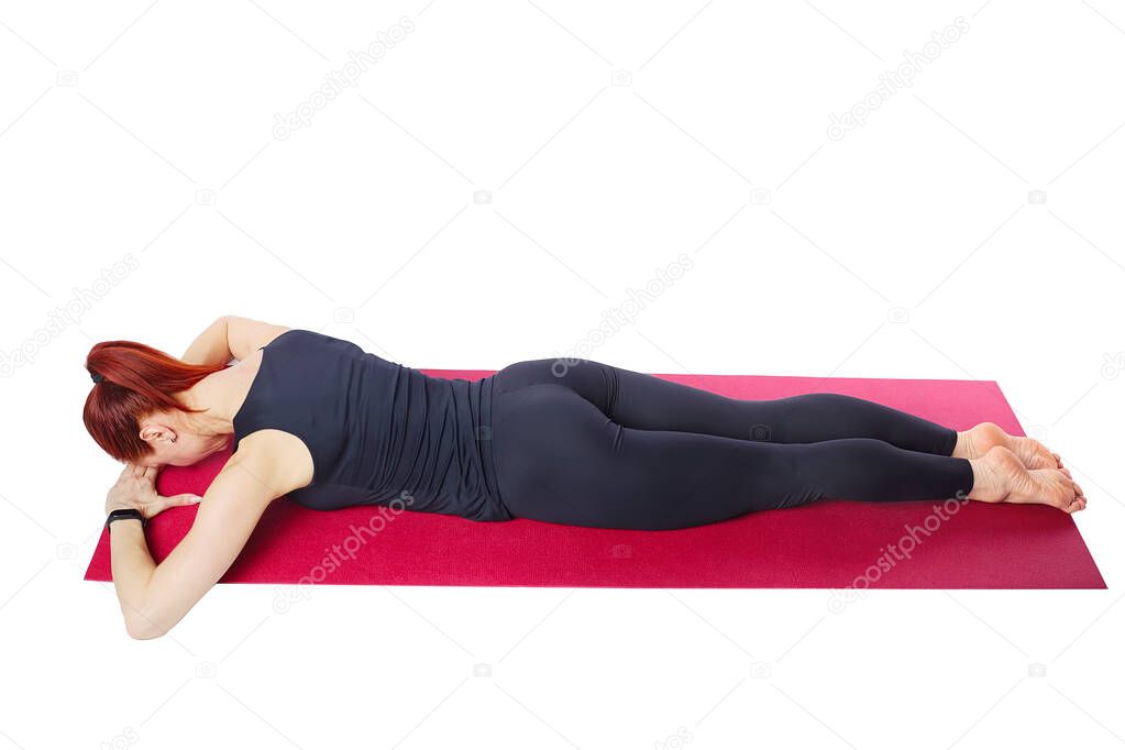 Pilates or yoga. A slender athletic girl performs the chest extension exercise lying on her stomach.