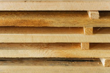 Tahtalar ve inşaat keresteleri marangozluk atölyesinde yatıyor. Ahşap işçiliği. Ürün tedarikçisinin arkaplanı.