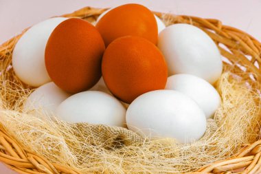 Bu, içinde doğal beyaz ve kahverengi tavuk yumurtaları olan sade bir hasır sepet. Doğal bir kırsal ürünün otantik fotoğrafı..