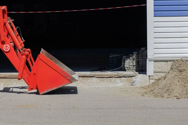 Repairs on the territory of the production base. This is an excavator bucket and a pile of sand on the asphalt. — Zdjęcie stockowe