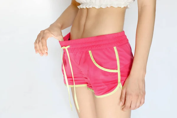 This is a close-up of a slender athletic female belly. The girl in pink shorts shows the elastic press — Fotografia de Stock