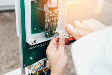 Kontrol ve ölçüm ekipmanlarının ayarlanması. Kerpetenle çalışan bir elektrikçinin ya da mühendisin elleri..