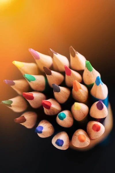 New color sharpened pencils on a dark background with sunlight or illumination. Abstract background on a creative theme. — Stock Photo, Image