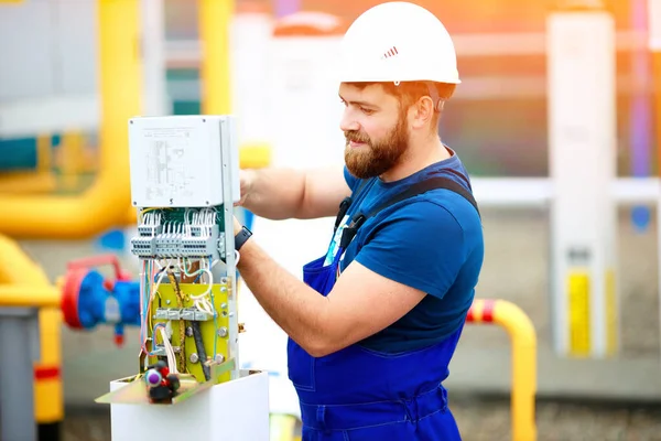 Egy képzett villamosmérnök egy nyári napon ellenőrző és mérőberendezést állít fel egy ipari létesítményben.. — Stock Fotó