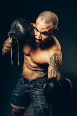 Karanlık bir arka planda çıplak gövdesi olan kaslı bir boksörün stüdyo resmi. Latin Amerikalı yumrukcular saldırıyor..