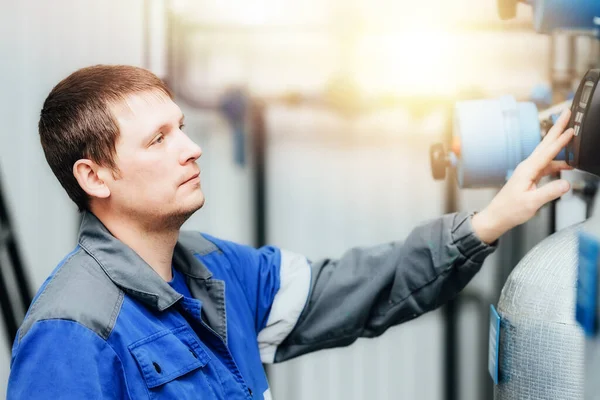 En man i arbetskläder kontrollerar sensorerna i pannan eller kompressorstationen. Systemövervakning. — Stockfoto