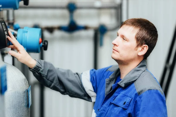 En man i arbetskläder kontrollerar sensorerna i pannan eller kompressorstationen. Systemövervakning. — Stockfoto