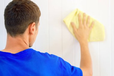 Elinde bez parçası olan bir adam odanın içindeki duvarı yıkıyor..