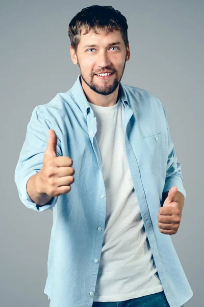 Πορτρέτο ενός ευτυχισμένου Καυκάσου χαμογελά και δείχνει τους αντίχειρες του επάνω. Θετικός τύπος με καθημερινά ρούχα. — Φωτογραφία Αρχείου