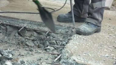 Bir işçi yaz günü bir kaya matkabıyla yol yüzeyini tamir eder. İnşaat yolda işliyor..