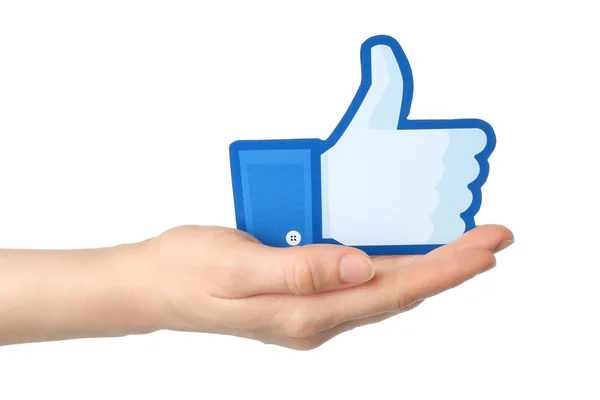 Hand holds facebook thumbs up sign printed on paper on white background — Stock Photo, Image