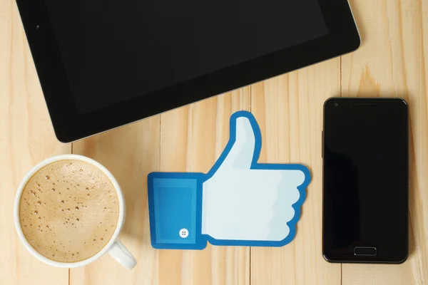 Facebook pouces vers le haut signe imprimé sur papier et placé sur fond en bois avec café, iPad et téléphone intelligent — Photo