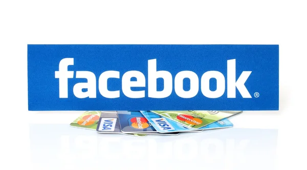 Logo Facebook dicetak di atas kertas dan ditempatkan di kartu Visa dan MasterCard pada latar belakang putih — Stok Foto