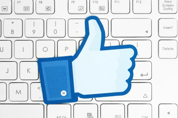 Facebook thumbs up sign printed on paper and placed on white keyboard — Stock Photo, Image