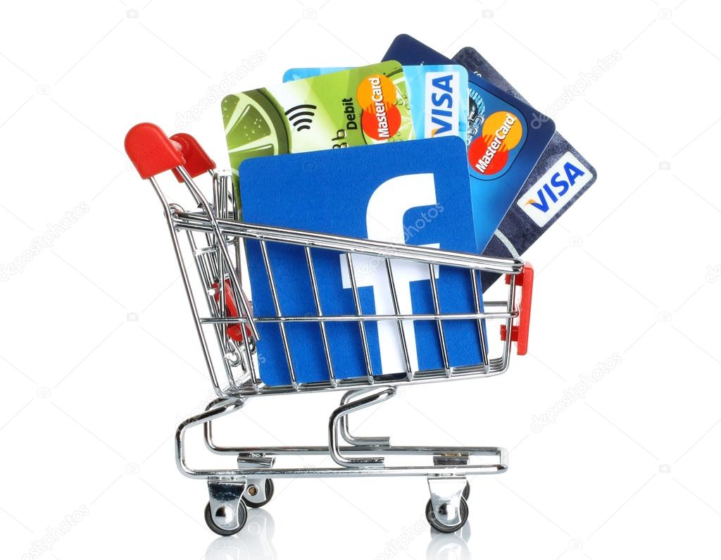 KIEV, UKRAINE - MARCH 21, 2015: Facebook logo printed on paper and placed into shopping cart with cards Visa and MasterCard on white background.New Facebook payment concept.