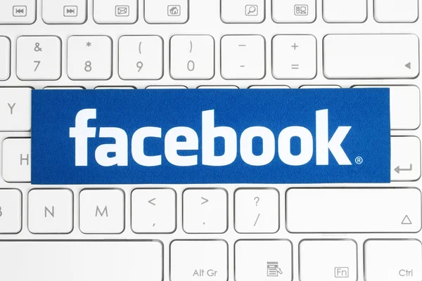 Facebook logo printed on paper and placed on white keyboard — Stok fotoğraf