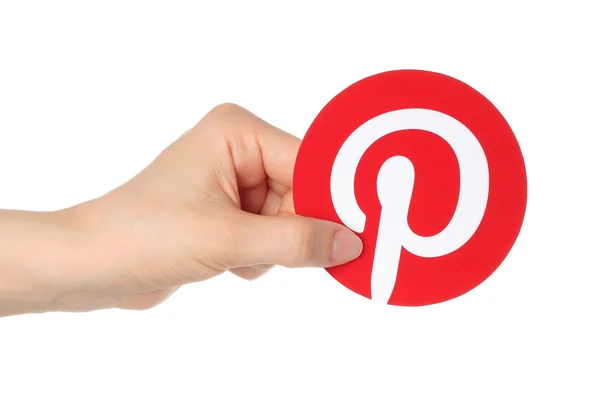 Hand holds Pinterest logotype printed on paper