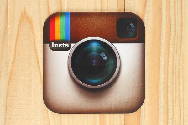 Instagram logotype camera printed on paper and placed on wooden background — Stockfoto