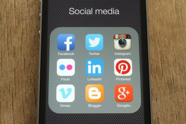iPhone with popular social media icons on its screen on wooden background