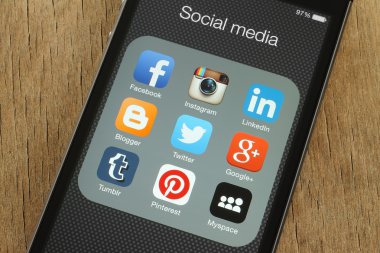 iPhone with popular social media icons on its screen on wooden background