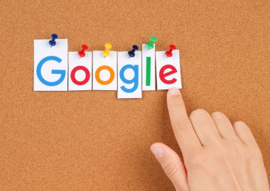 New Google logotype printed on paper, cut and pinned on cork bulletin board with hand
