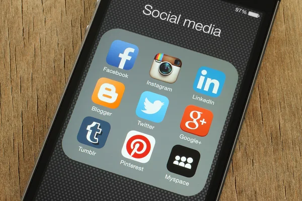 IPhone con icone popolari dei social media sul suo schermo su sfondo di legno — Foto Stock