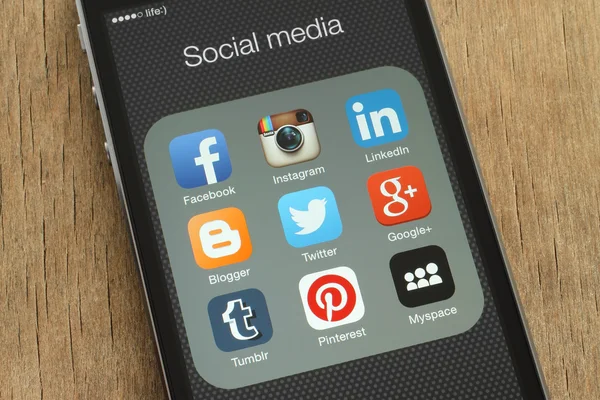 IPhone con icone popolari dei social media sul suo schermo su sfondo di legno — Foto Stock