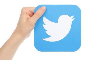 Hand holds twitter icon printed on paper. Twitter is an online social networking service that enables users to send and read short messages