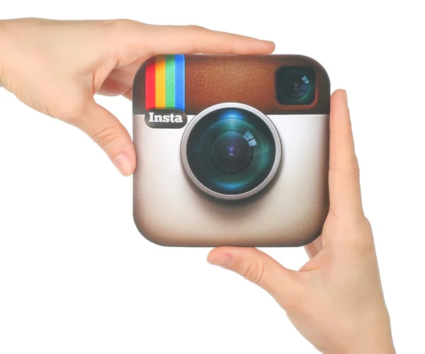 Hands hold Instagram logo printed on paper on white background. Instagram is an online mobile photo-sharing, video-sharing service — Stock Photo, Image