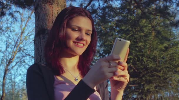 Bir parkta onun akıllı telefon kullanan genç öğrenci kız — Stok video