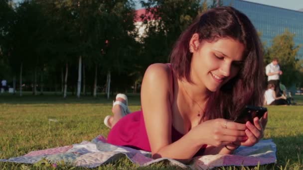 Wanita muda yang bahagia menggunakan smartphone di taman — Stok Video